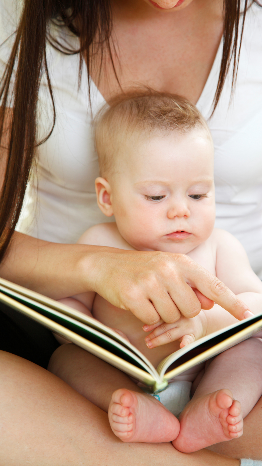 Madre señalando las imágenes de un libro mientras su bebé observa con atención