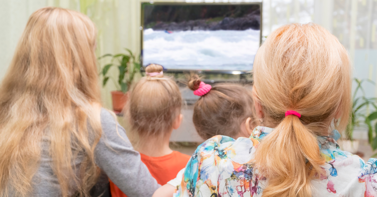 Familia acompañando a las niñas y niños frente a la televisión