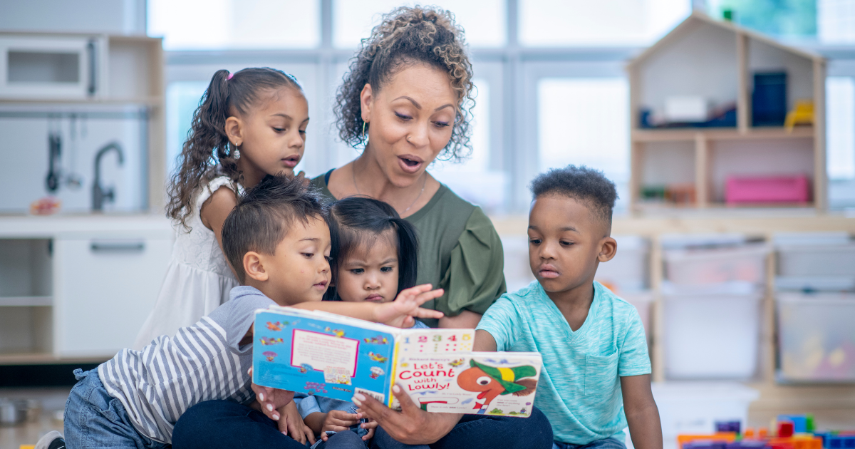 Una educadora leyendo un cuento a un grupo de niñas y niños sentados a su alrededor